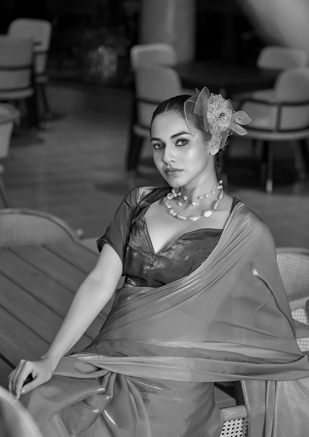 Black-and-white portrait of a seated model wearing a saree and floral headpiece.